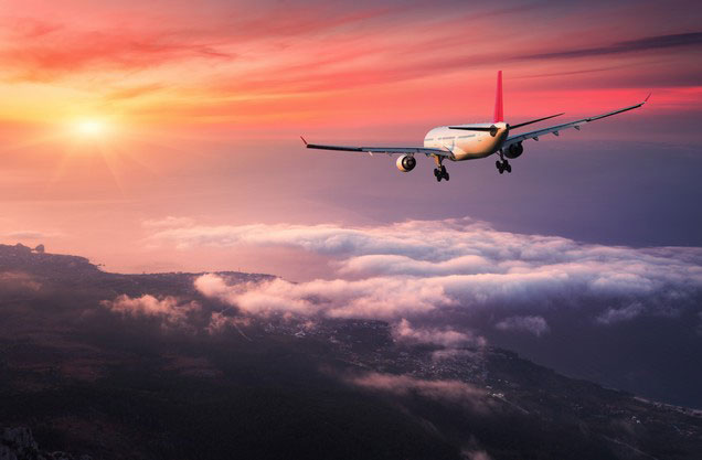 Athens Airport El.Venizelos (to or from) Ancient Olympia: a plane flies between the clouds as the sun sets