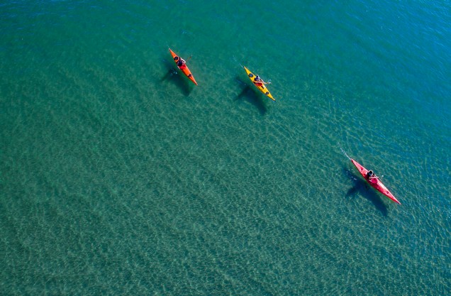 Sea Kayaking in Navarino bay: three people are kayaking in the turquoise waters of Navarino