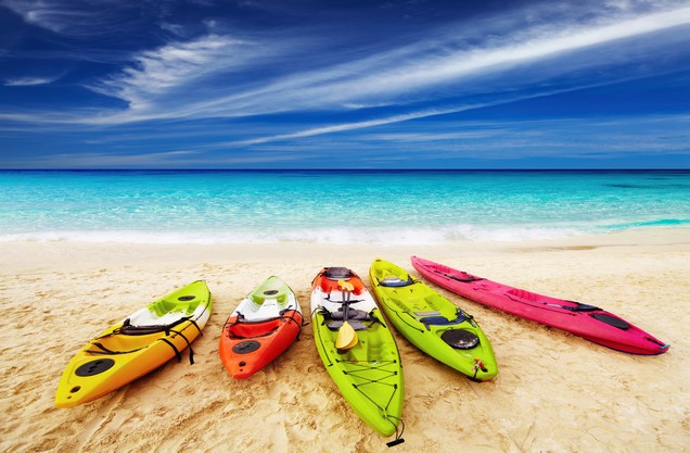 Sea Kayaking in Kalamata: five colored kayaks canoes lined up on the sand in Kalamata